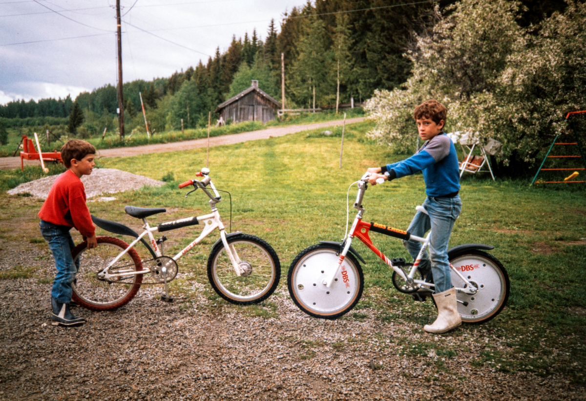 Stange, Espa, Kjeldsrud gård. Gutta sykler på gårdsplassen, den gamle smia sees i bakgrunnen.
Edvard Romsaas Borgersen (7år) og Anders Romsaas Borgersen (10 år) med hver sin nye DBS cross sykkel.