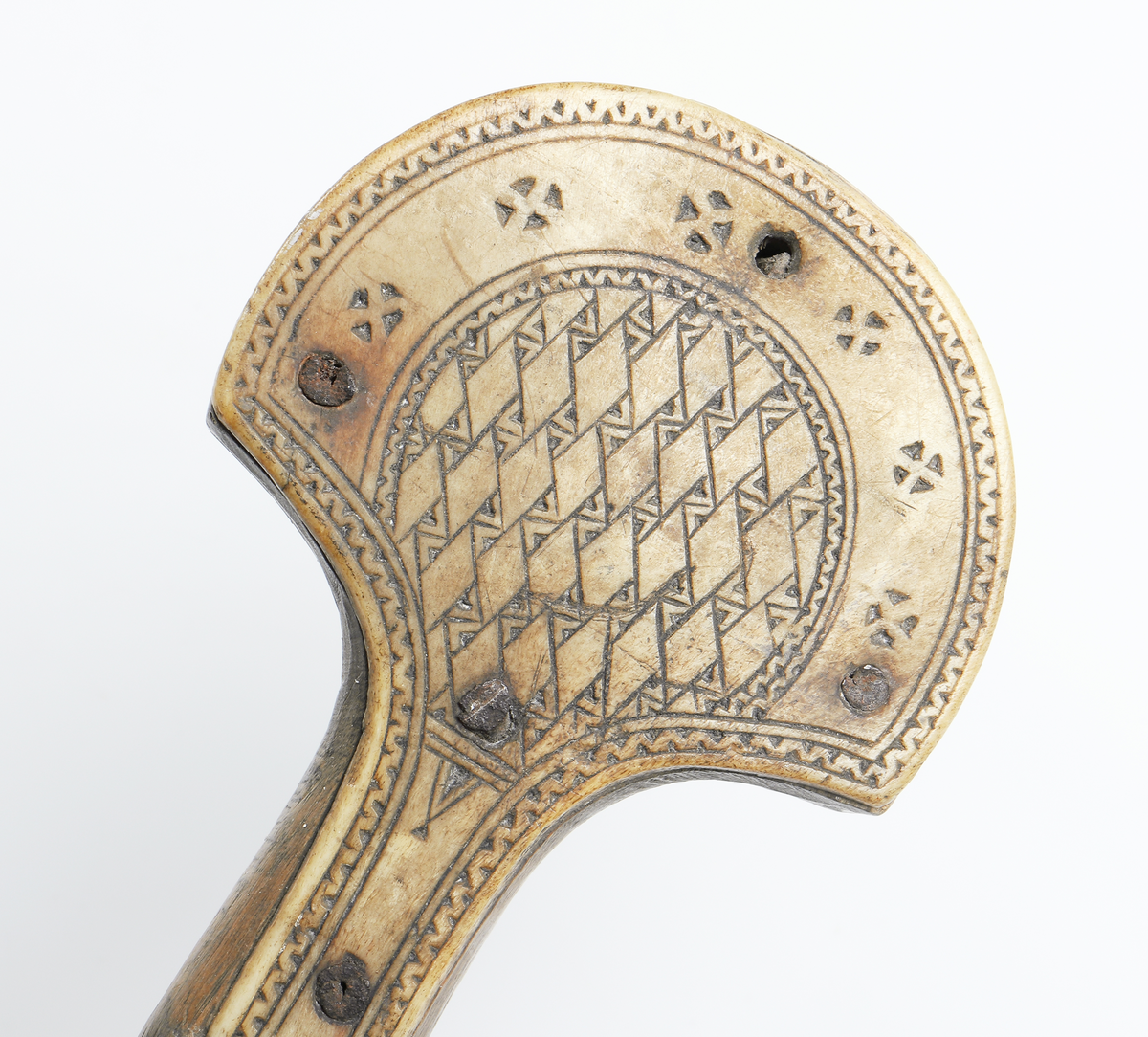 Käpp av trä med benförsedd knopp. Benstyckerna, ett på vardera sidan, är dekorerade med geometriska figurer, fastsatta med fem spikar. Inuti käppen har man lagt i stenar eller liknande så att den skramlar när man rör den. Från Gällivare.