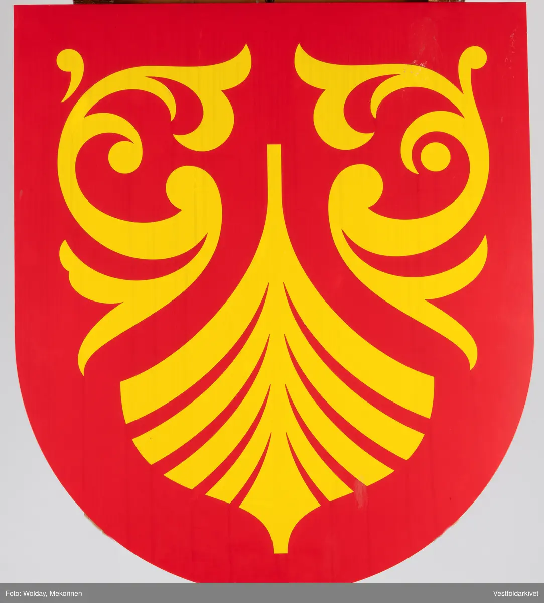 Et skilt i metall, i rødt og gult med logoen til Fylket Vestfold og Telemark som eksisterte fra 2020-2023