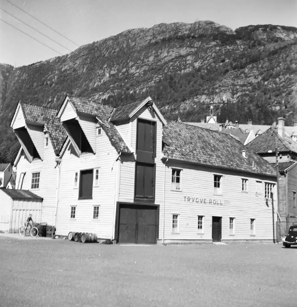 Bildet i sort-hvitt viser en sjøbod med flere vindeheisarker. 