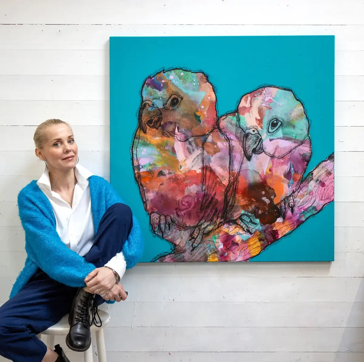 Gunilla Holm Platou sitjande på ein krakk framom sitt eige kunstverk