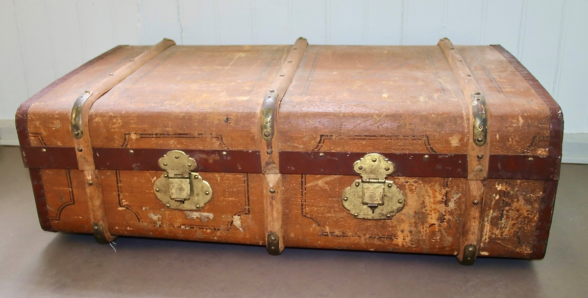 Låsbar rektangulær lysbrun koffert med metallbeslag på sidene, og trebeslag forsterket med messing. Kofferten er merket med romertall III på lokket. Hemper i lær som håndtak på hver kortside. To låser i messing. Hovedmaterialet er trolig tre. Kofferten er kledt med tekstil innvendig, og oljelerret (?) på utsiden. Enkel dekormaling