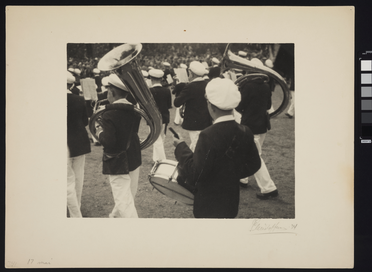 Et guttekorps marsjerer med sine musikkinstrumenter, iført uniform.