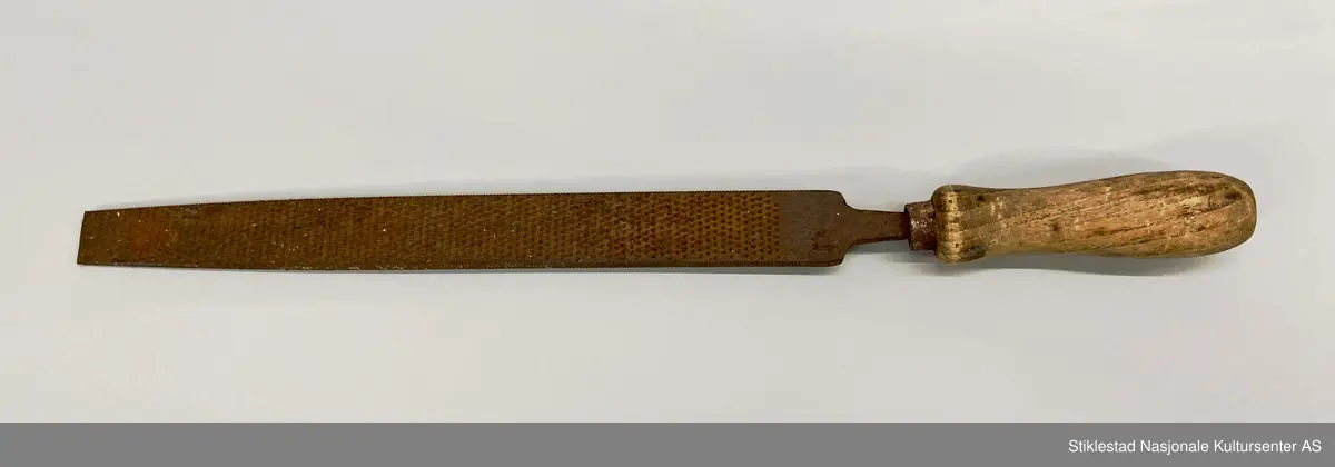 Fabrikkprodusert rasp med dreid skaft av løvtre. Raspa er flat på begge sider og smalner av mot enden, spissen er knekt. Holk i blikk. Innsnevring i nedre del av skaft for bedre grep. En god del rust.