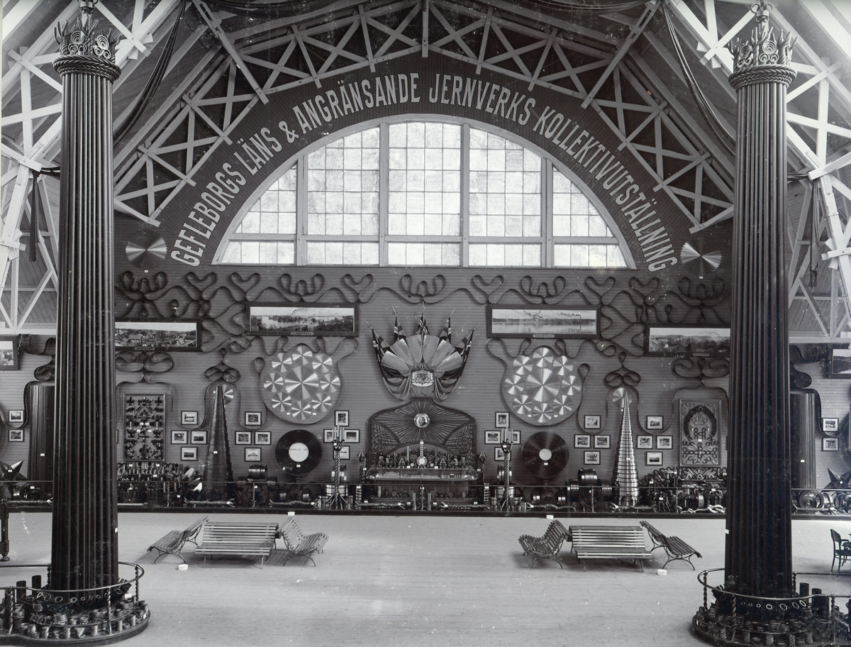 Gefle-utställningen 1901. En Lantbruks-, industri- och slöjdutställning. Utställningarna höll till på Norr där ett järnvägsspår lagts, norrlandsföretag visade sina produkter. Utställningen pågick i 65 dagar. Bild på utställningshall där orden "Gefleborg Läns & Angränsande Jernverks Kollektivutställning" står skrivet över fönstret.