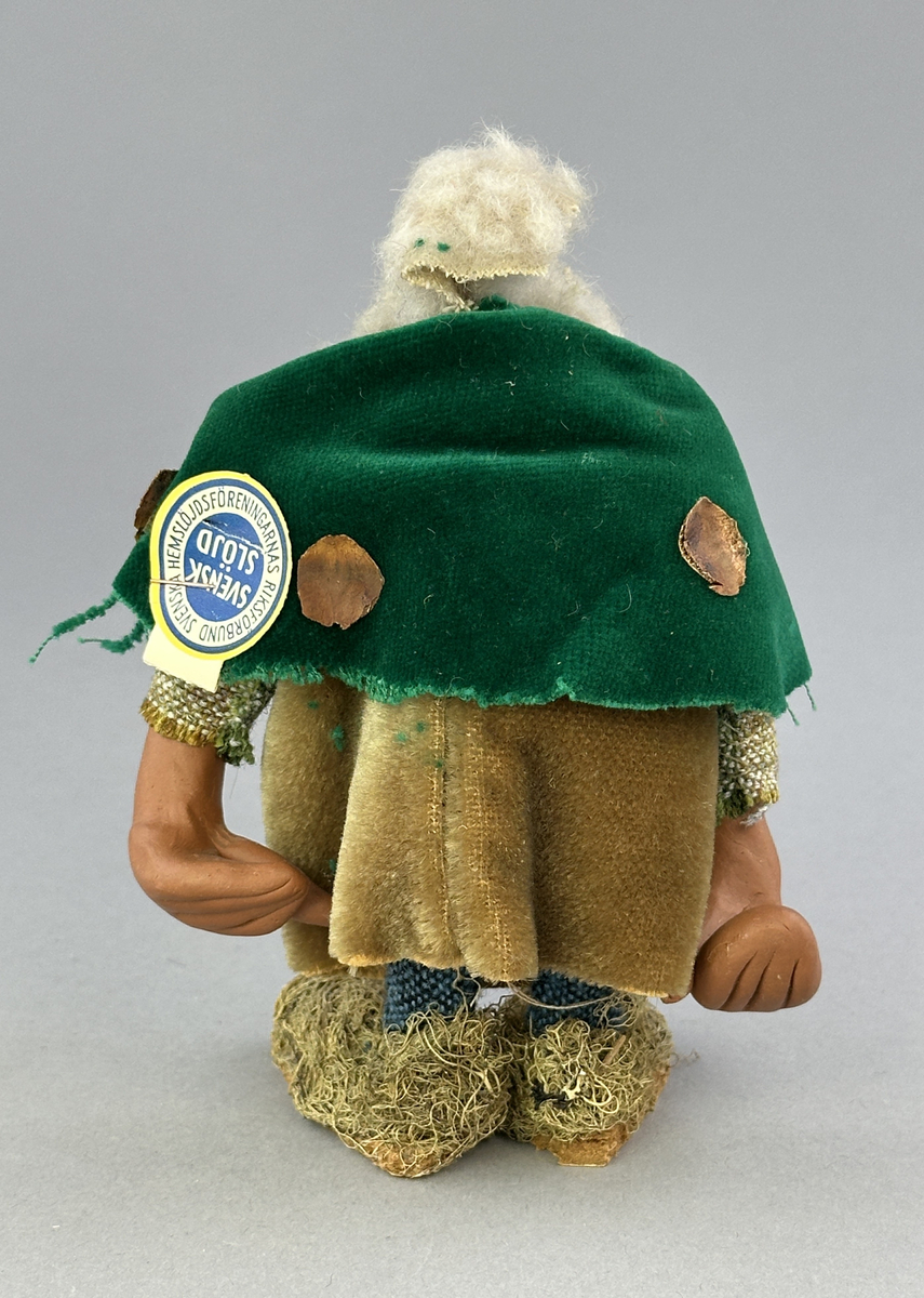 Trollgumma med stora fötter och händer. Är klädd i sammets kjol och sammets cape prydd med kott-blad.