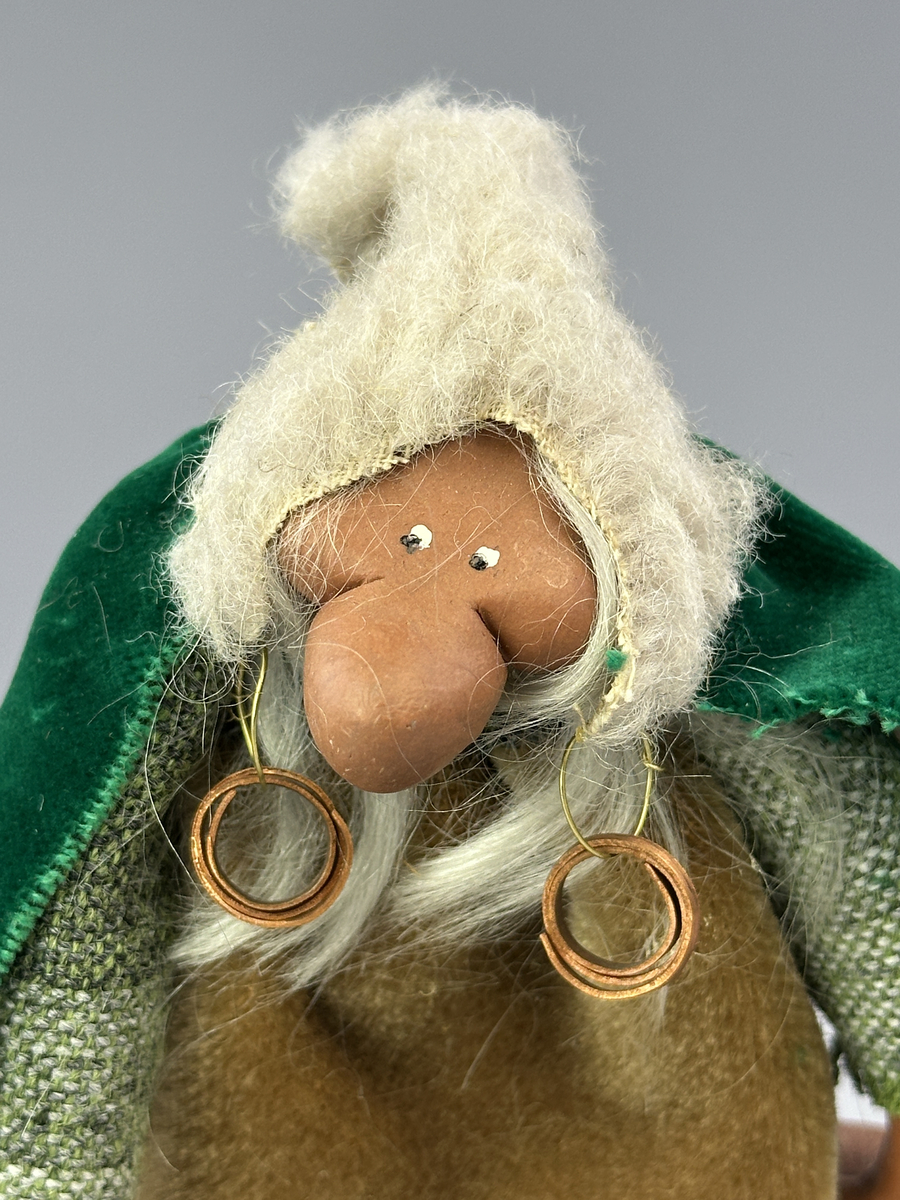 Trollgumma med stora fötter och händer. Är klädd i sammets kjol och sammets cape prydd med kott-blad.