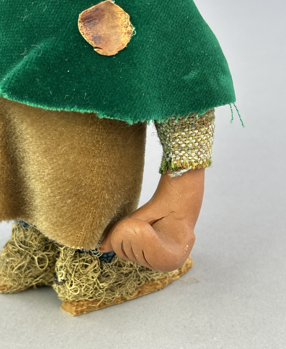 Trollgumma med stora fötter och händer. Är klädd i sammets kjol och sammets cape prydd med kott-blad.
