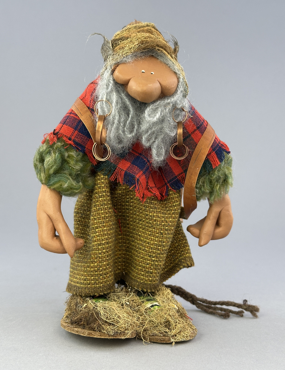 En trollgumma med näverkont på ryggen. Kläder av tyg, skor och mössa av lav och kottfjäll.