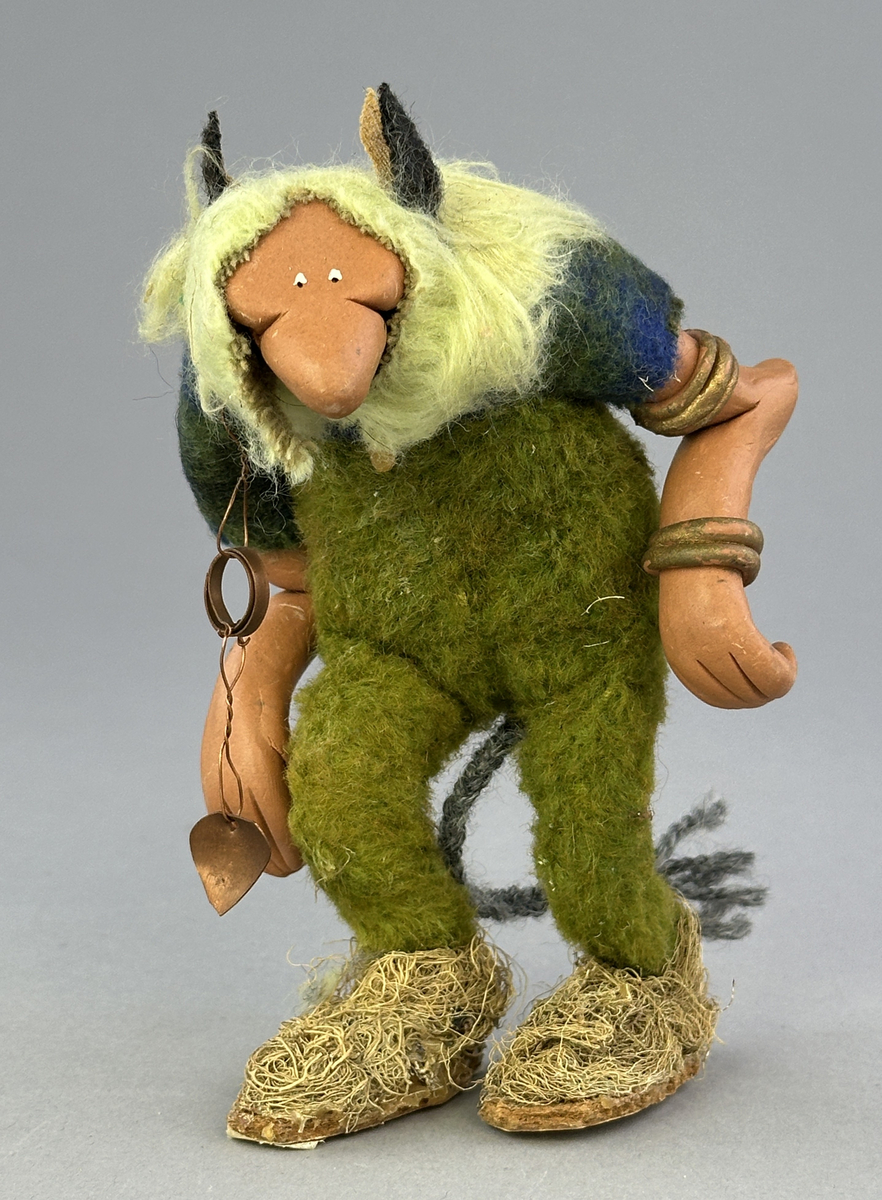 En krokig trollgubbe med böjda knän och rygg. Har lavklädda skor, koppar-örhänge och "guld" ringar på armarna. Är klädd i gröna byxor och blågrön skjorta.


