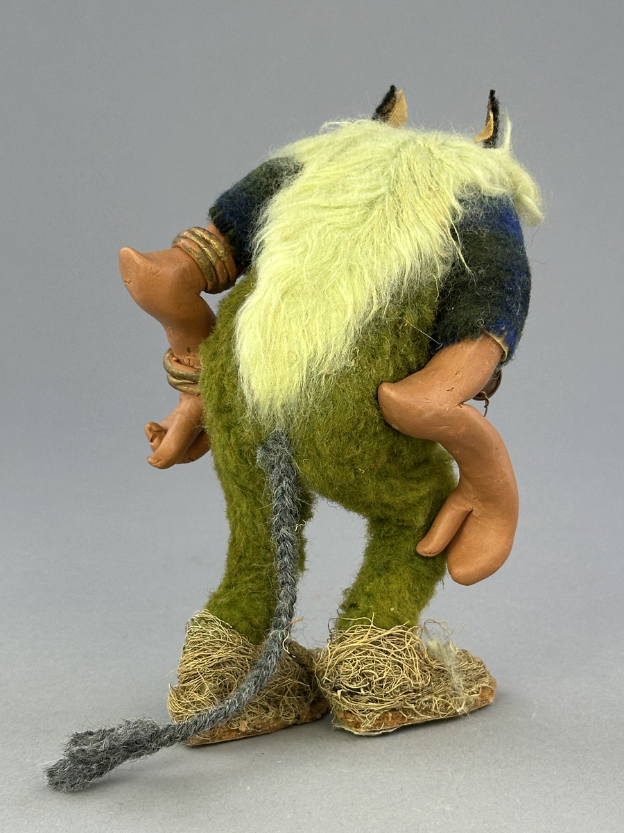 En krokig trollgubbe med böjda knän och rygg. Har lavklädda skor, koppar-örhänge och "guld" ringar på armarna. Är klädd i gröna byxor och blågrön skjorta.


