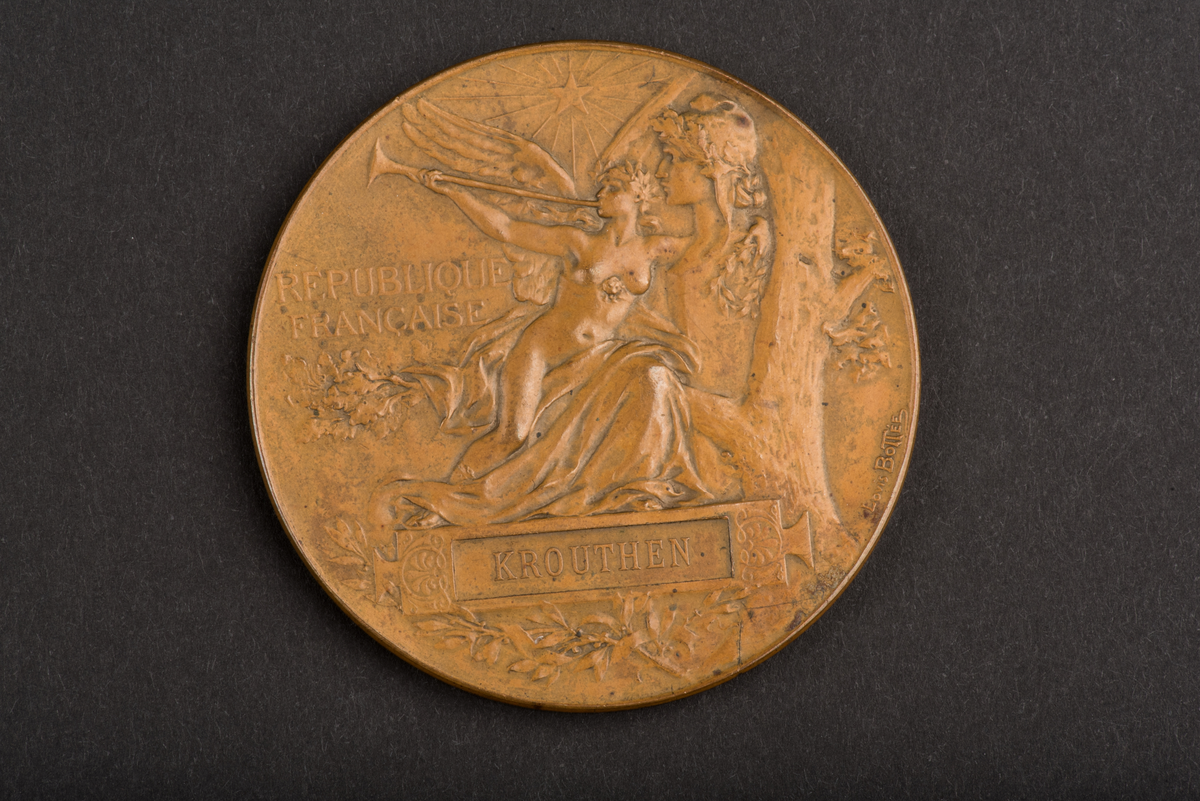 Åtsidan: en man lagerkrönande en kvinna, inskription: EXPOSITION UNIVERSELLE 1889.
Frånsidan: en kvinna blåsande trumpet framför Napoleons byst, inskription: REPUBLIQUE FRANCAISE.