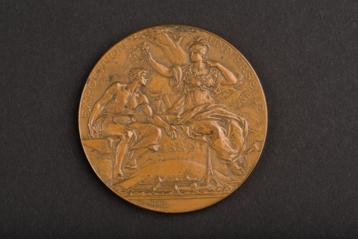 Åtsidan: en man lagerkrönande en kvinna, inskription: EXPOSITION UNIVERSELLE 1889.
Frånsidan: en kvinna blåsande trumpet framför Napoleons byst, inskription: REPUBLIQUE FRANCAISE.