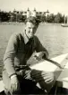 Fotografi ur Detlow von Brauns album. Detlow von Braun vid rodret utanför Saltsjöbaden i Nacka.