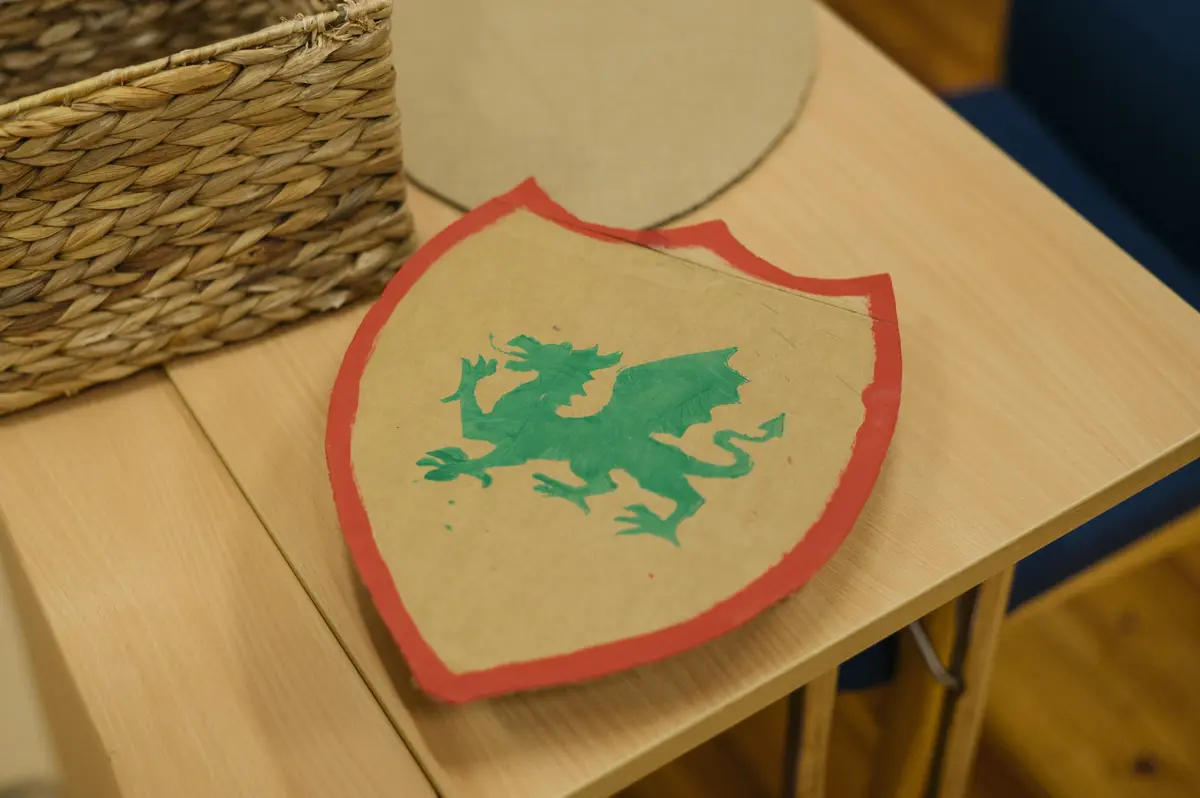 Viser et skjold med rød kant, i midten er det en grønn drage på fire ben.