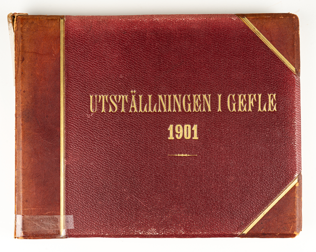 Fotoalbum från Gävleutställningen 1901. Album med röda pärmar och text i guld.