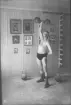 Kraftkarl ifrån atletklubben Heros poserande inomhus med hantelvikter tidigt 1900-tal.