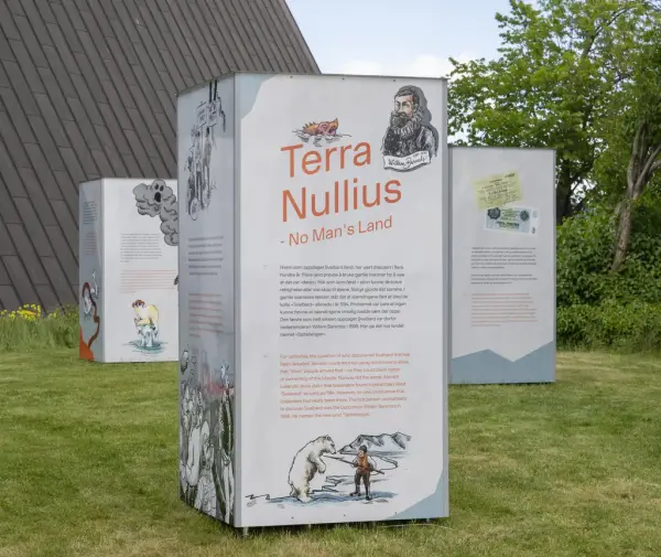 Utendørs utstillingssøyle med tittelen «Terra Nullius – No Man’s Land», omgitt av flere informasjonsstolper med tekst og illustrasjoner på gressplen.