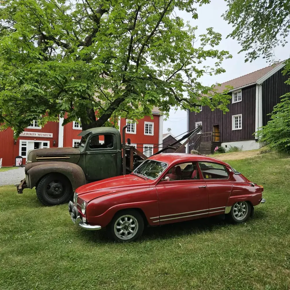 To veteranbiler, en rusten kranbil og en rød personbil i hagen foran Ringerikes Museum 