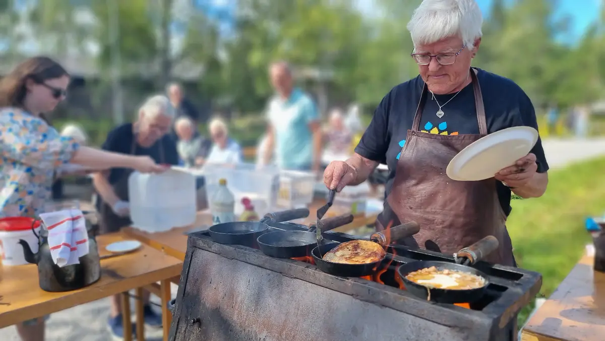 Man i förkläde steker kolbullar på stekhäll.