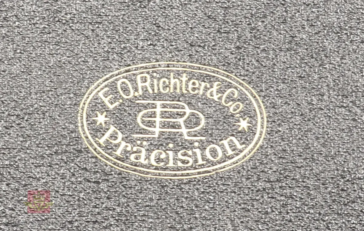 Passersett i etui, består av atten deler (en del mangler). Etuiet består av sort skinntrukket treverk og har fløyelsbelagt innside i svart farge. Produsentens logo inne i lokket.