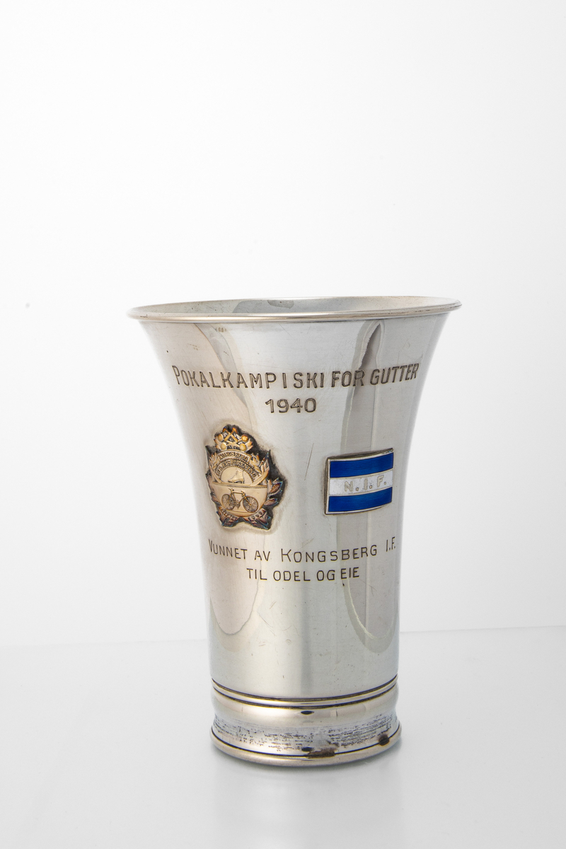 Enkel pokal uten stett, med to emblem (Kongsberg IF og N.I.F) og inskripsjon.