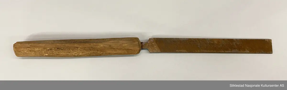 Fabrikkprodusert metallfil med skråstilte filspor, enkelthogd på begge sider. Montert på et langt skaft i løvtre, grovt teljet/spikket. Fila har et stempel, men vanskelig å lese . Mye rust