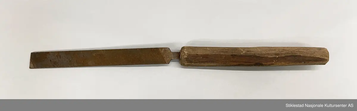 Fabrikkprodusert metallfil med skråstilte filspor, enkelthogd på begge sider. Montert på et langt skaft i løvtre, grovt teljet/spikket. Fila har et stempel, men vanskelig å lese . Mye rust