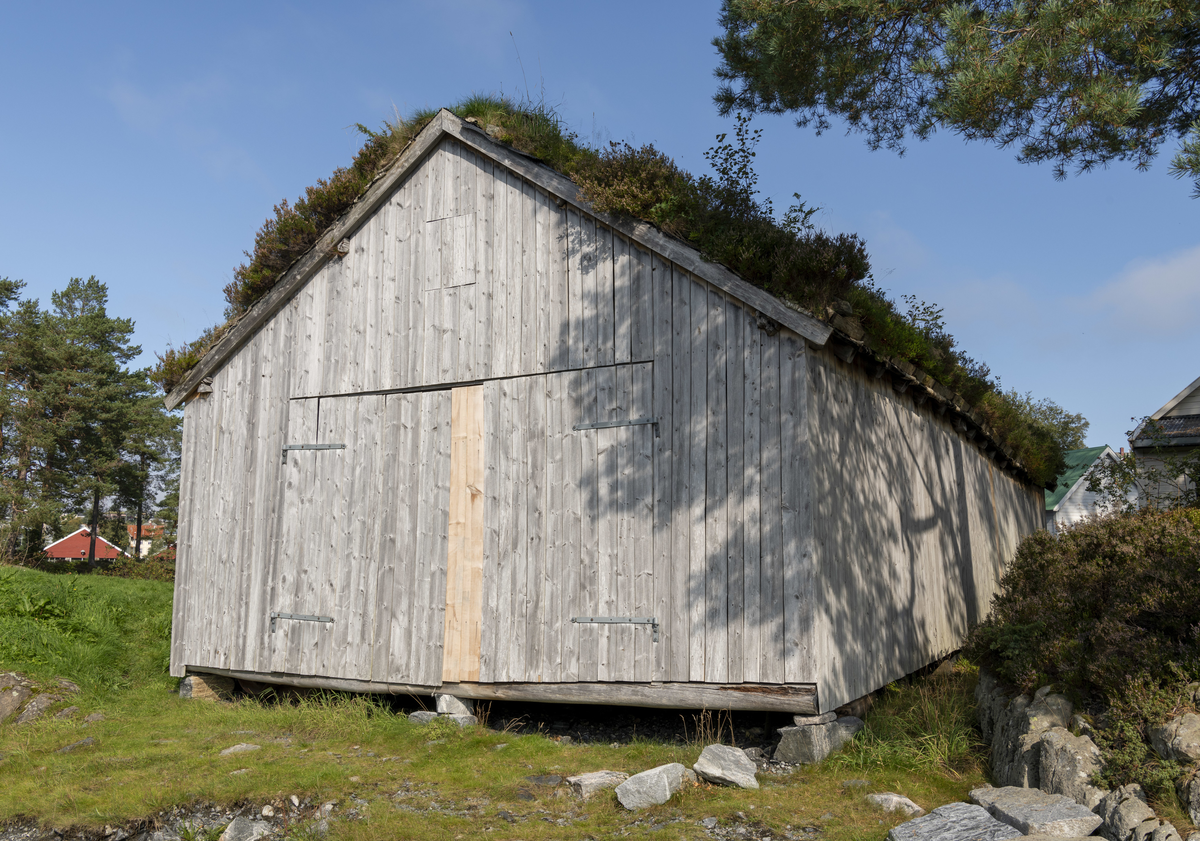 Grindbygg med ståande låvepanel og torvtak.