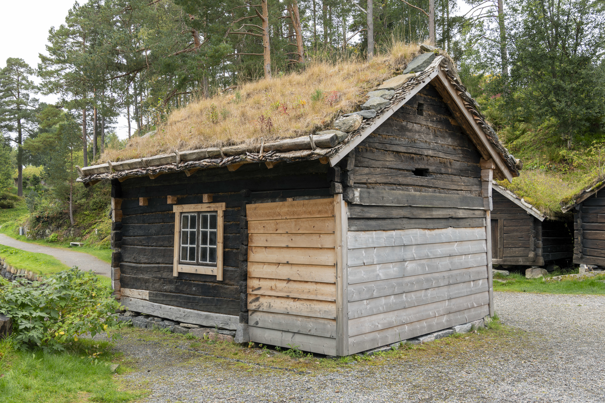 Lafta tømmer med ei dør. Torvtak.