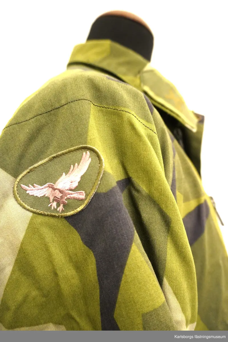 Jacka m/1990 är sydd i kamouflagetryckt varpsatin av bomull samt polyester. Fältjackans ärmar och rygg är skurna i ett stycke, med sömn mitt på ryggen. Ärm och framstycke möts i reglansömn. I nederkanten och i midjan finns snören för reglering av vidden. Yttertyg och foder bildar fickor till två bröstfickor och två sidfickor med blixtlås. Jackan stängs framtill, med ett tvåvägs öppningsbart blixtlås som täcks av ett vindskydd utrustat med tryckknappar. På kragen finns märke för överstelöjtnant på vänster sida samt ett märke för kavalleriet på höger sida. På vänster arm ett livregementets husarer-märke. Storlek: 180/75.