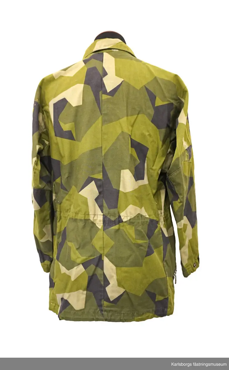 Jacka m/1990 är sydd i kamouflagetryckt varpsatin av bomull samt polyester. Fältjackans ärmar och rygg är skurna i ett stycke, med sömn mitt på ryggen. Ärm och framstycke möts i reglansömn. I nederkanten och i midjan finns snören för reglering av vidden. Yttertyg och foder bildar fickor till två bröstfickor och två sidfickor med blixtlås. Jackan stängs framtill, med ett tvåvägs öppningsbart blixtlås som täcks av ett vindskydd utrustat med tryckknappar. På kragen finns märke för överstelöjtnant på vänster sida samt ett märke för kavalleriet på höger sida. På vänster arm ett livregementets husarer-märke. Storlek: 180/75.