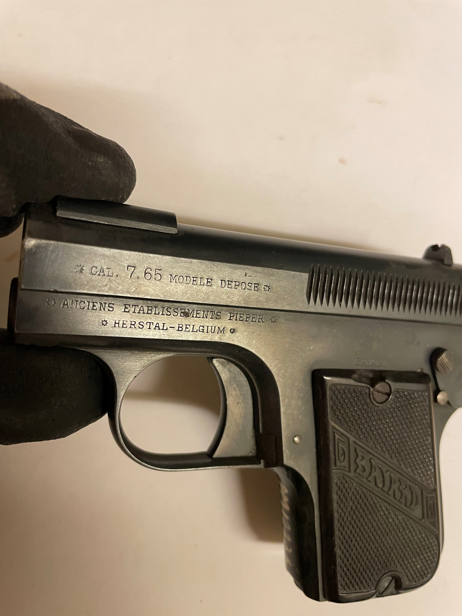Pistol, halvautomatisk med magasin i kolven.  En säkerhetsspärr finns på vapnet. Kaliber 7,65 mm. 

Fabriksemblemet "BAYARD" inom ett band över kolven. 
På sidan text: " CAL. 7.65 MODELE DEPOSE. ANCIENS ETABLISSEMENTS PIEPER. HERSTAL - BELGIUM.

På ovansidan: BREVETE S. G. D. G. PATENTED SEPT. 8 1908

Tillverkningsnummer: 49926.