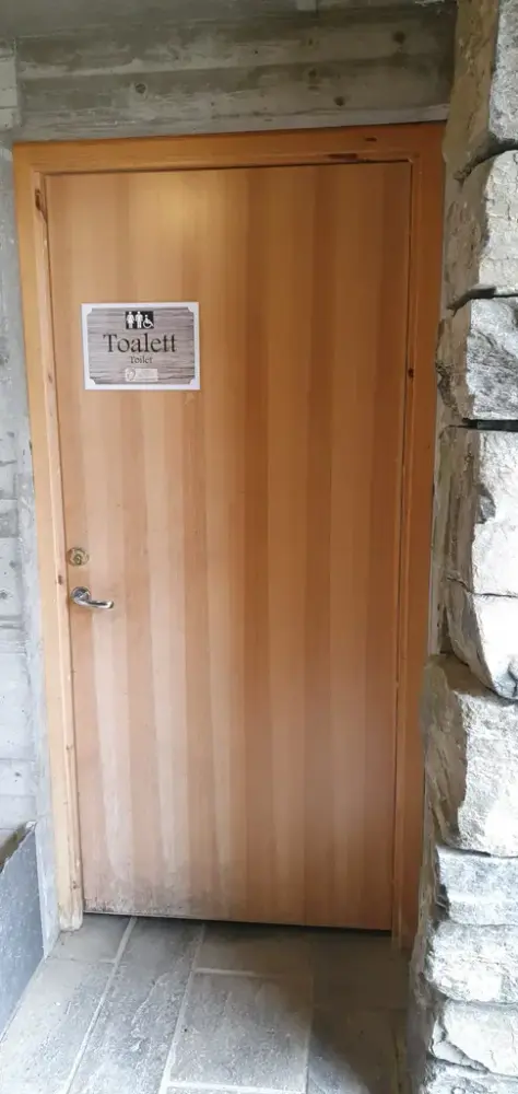 Tredør til toalett på utsida av informasjonsbygget. Døropning er 80 cm brei.
