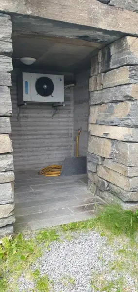 Opning i steinmur som viser tilkomsten til ytterrommet der døra inn til toalettet på utsida av bygget er.