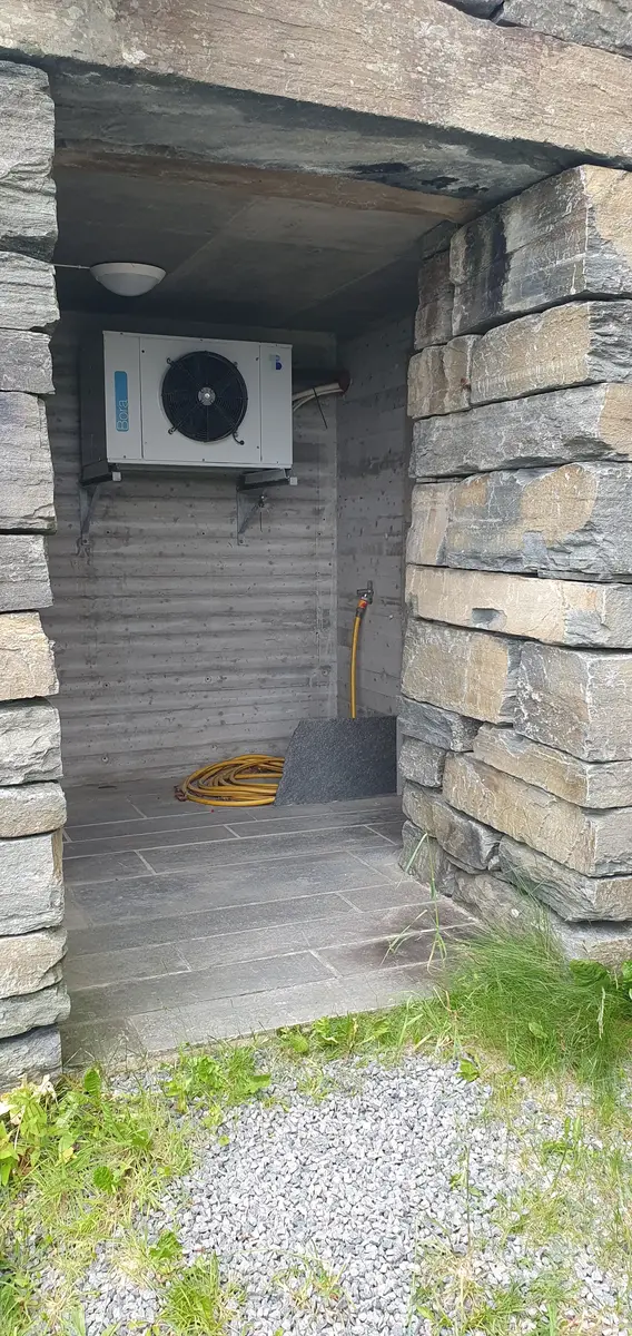 Opning i steinmur som viser tilkomsten til ytterrommet der døra inn til toalettet på utsida av bygget er.