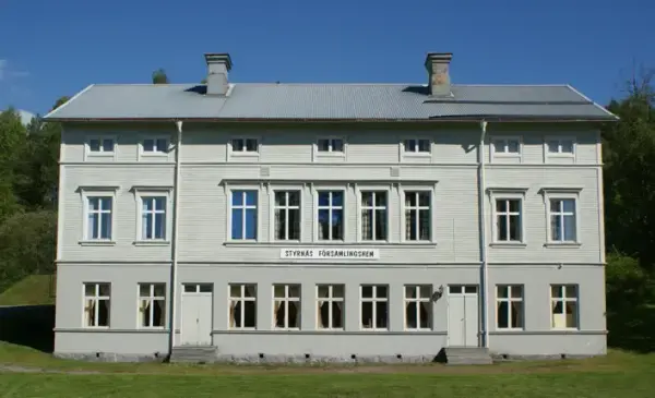 En grå, stor symmetrisk byggnad med många fönster: Styrnäs församlingshem.