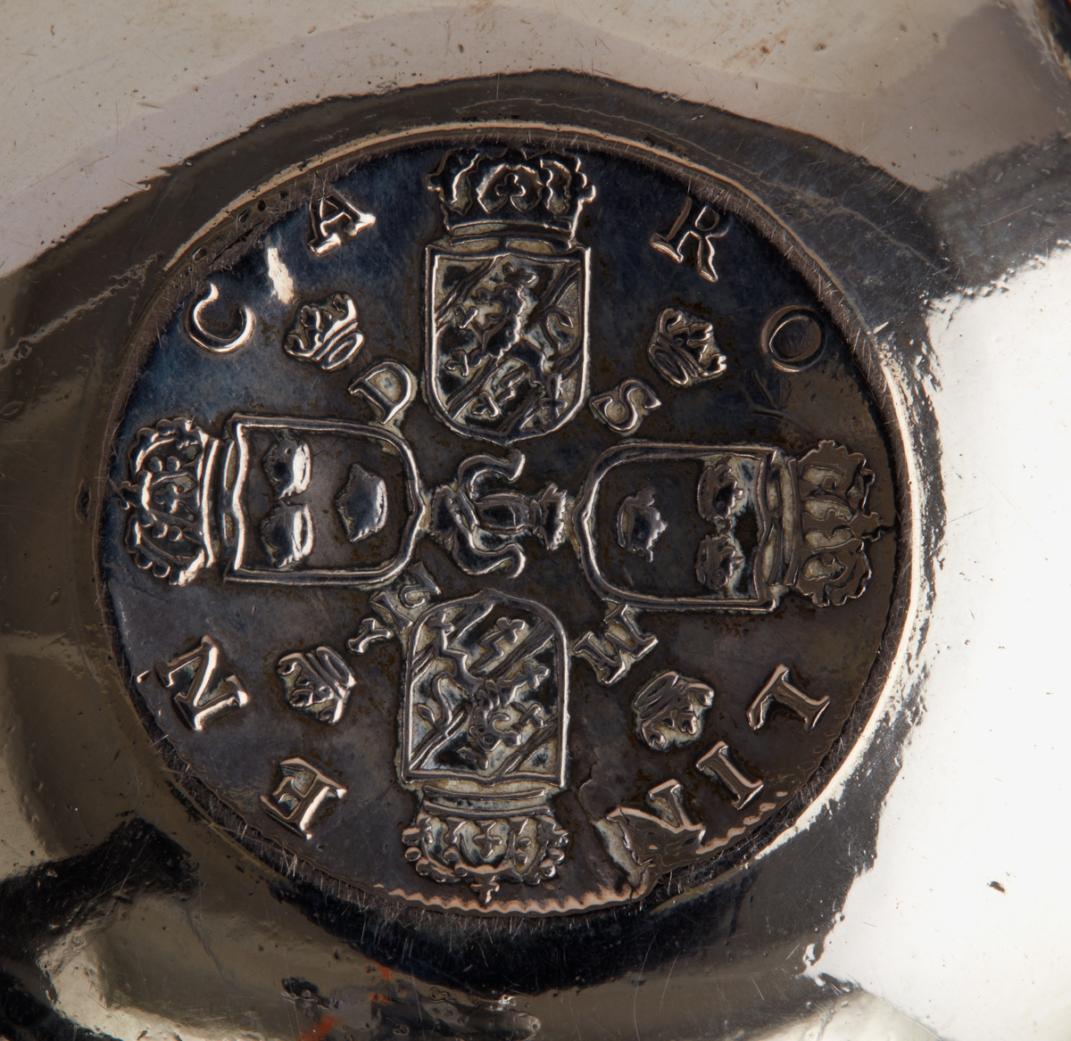 Skål av förgyllt silver. Rundad botten. Smalt utställt bräm. Tio infällda kopparmynt "1 daler silvermynt" med olika motiv. I botten ett infällt silvermynt: "Dominvs protector mevs, X II, 1718". graverat under brämet: "Då Suea Land i Krig och örling diúpat Låg man úppå Kopparmynt Slikt Bilder Präglad Såg". Ostämplad.

Donation 1991 genom testamente efter makarna Tor och Margareta Ärje.