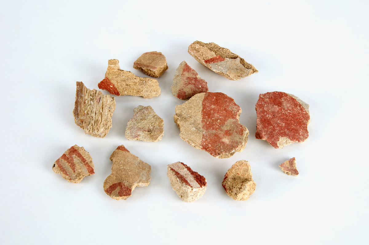 En samling av fragment av målad puts och bruk med kalkputs och bemålning. 17 fyndaskar med fragment i olika storlekar.

Fyndask 1: Totalt 13 fragment med röd och vit färg, en ser ut att ha träavtryck (varit fäst mot ett trästycke).

Fyndask 2: Totalt 7 fragment alla utom en har röd och vit färg, endast en med gråaktig obehandlad puts. 

Fyndask 3: Totalt 1 större fragment med röd och vit färg på enda sidan.

Fyndask 4: Totalt 4 fragment alla utom en med röd och vit färg, endast en med vit puts. 

Fyndask 5: Totalt 3 fragment med röd och vit färg, varav en är sotig. 

Fyndask 6: Totalt 3 fragment med röd och vit färg, en mycket tydlig medan de andra två mer diffusa. 

Fyndask 7:  Totalt 27 fragment, 24 av dessa är bemålade med röd och vit färg, 3  fragment med gråaktig obehandlad puts. 

Fyndask 8: Totalt 5 fragment, varav 4 större och en mycket liten. Alla större fragment med olika karaktär. En med vit kalkbruk och utan putsad yta, en annan med svart och röd putsad yta. Det tredje fragmentet har lite rödfärgad puts bevarad och på andra sidan ser det ut att ha träavtryck (varit fäst mot ett trästycke). Det fjärde fragmentet har en mer brungrå nyans. I fyndasken låg en lapp med text N. om V. portalen. 

Fyndask 9: Totalt 13 fragment, varav ett större fragment med svart och rödmålad puts. Ett annat fragment med svart och vitmålad puts, det tredje fragmentet har endast svartmålad puts. Sedan finns tre rödmålande putsfragment, samt tre fragment med röda linjer. Fyra fragment är ytterst små och intetsägande.

Fyndask 10: Totalt 9 fragment samt smådelar varav två har rött färgfragment. Det största fragmentet samt fyra andra är svart- och rödmålat. Tre putsfragment har röda linjer.
 
Fyndask 11: Totalt 1 fragment med röda linjer samt en mindre del med blågråa linjer. 

Fyndask 12: Totalt 1 fragment med blågrå rundad linje samt samt en mindre punkt eller koncentration nedanför.  

Fyndask 13: Totalt 5 fragment varav två med rödmålad puts. De andra tre har linjer. 

Fyndask 14: Totalt 1 fragment med vit och rödmålad puts, med flertal linjer som eventuellt kan vara del av en bokstav.
 
Fyndask 15: Totalt 1 fragment med vit och svartmålad puts, med flertal linjer som eventuellt kan vara del av en större figur. Ena delen syns en större koncentration som skulle kunna vara en fågel. 

Fyndask 16: Totalt 1 fragment med vit och rödmålad puts, med flertal rundade linjer som eventuellt kan vara del av växtlig dekor.

Fyndask 17: Totalt 1 fragment med rödmålad puts, med en vit linje.