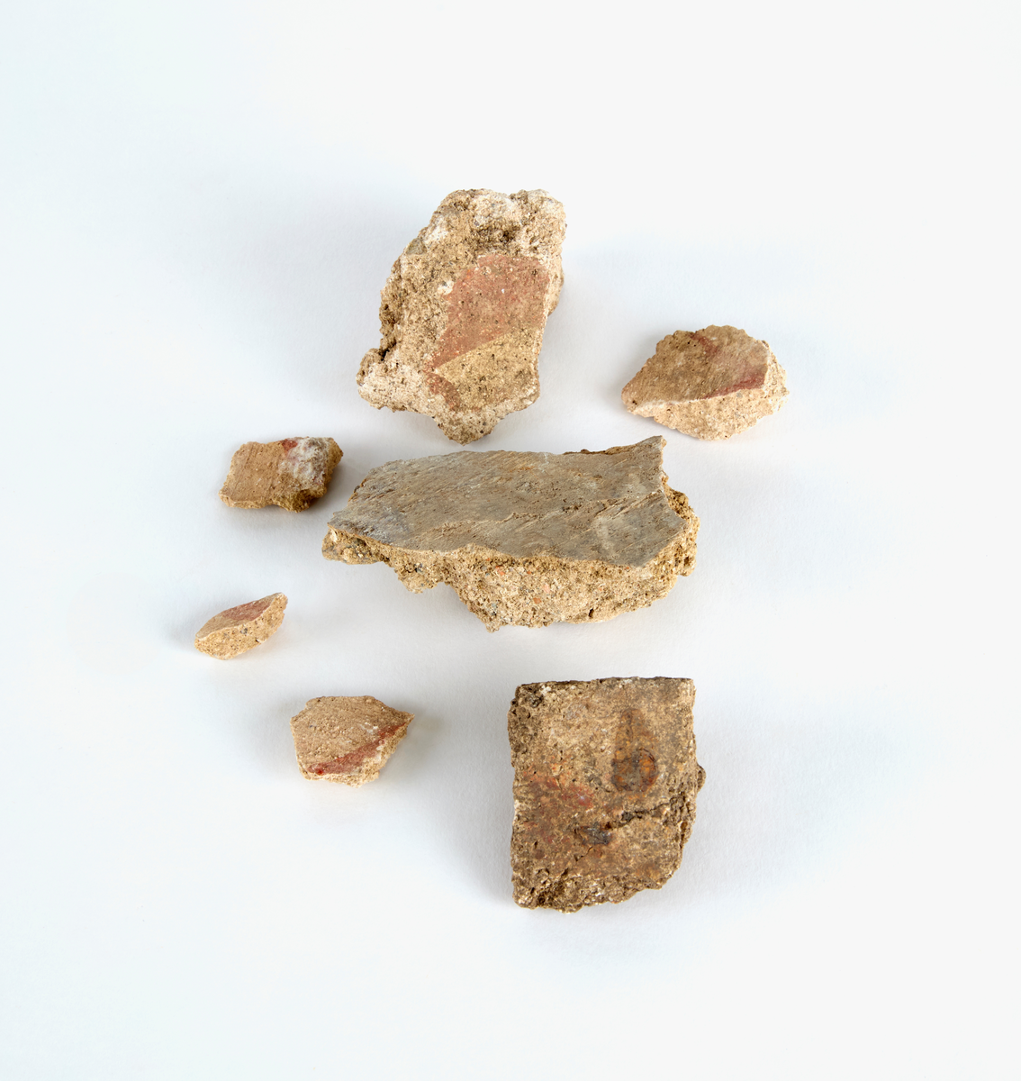 En samling av fragment av målad puts och bruk med kalkputs och bemålning. 17 fyndaskar med fragment i olika storlekar.

Fyndask 1: Totalt 13 fragment med röd och vit färg, en ser ut att ha träavtryck (varit fäst mot ett trästycke).

Fyndask 2: Totalt 7 fragment alla utom en har röd och vit färg, endast en med gråaktig obehandlad puts. 

Fyndask 3: Totalt 1 större fragment med röd och vit färg på enda sidan.

Fyndask 4: Totalt 4 fragment alla utom en med röd och vit färg, endast en med vit puts. 

Fyndask 5: Totalt 3 fragment med röd och vit färg, varav en är sotig. 

Fyndask 6: Totalt 3 fragment med röd och vit färg, en mycket tydlig medan de andra två mer diffusa. 

Fyndask 7:  Totalt 27 fragment, 24 av dessa är bemålade med röd och vit färg, 3  fragment med gråaktig obehandlad puts. 

Fyndask 8: Totalt 5 fragment, varav 4 större och en mycket liten. Alla större fragment med olika karaktär. En med vit kalkbruk och utan putsad yta, en annan med svart och röd putsad yta. Det tredje fragmentet har lite rödfärgad puts bevarad och på andra sidan ser det ut att ha träavtryck (varit fäst mot ett trästycke). Det fjärde fragmentet har en mer brungrå nyans. I fyndasken låg en lapp med text N. om V. portalen. 

Fyndask 9: Totalt 13 fragment, varav ett större fragment med svart och rödmålad puts. Ett annat fragment med svart och vitmålad puts, det tredje fragmentet har endast svartmålad puts. Sedan finns tre rödmålande putsfragment, samt tre fragment med röda linjer. Fyra fragment är ytterst små och intetsägande.

Fyndask 10: Totalt 9 fragment samt smådelar varav två har rött färgfragment. Det största fragmentet samt fyra andra är svart- och rödmålat. Tre putsfragment har röda linjer.
 
Fyndask 11: Totalt 1 fragment med röda linjer samt en mindre del med blågråa linjer. 

Fyndask 12: Totalt 1 fragment med blågrå rundad linje samt samt en mindre punkt eller koncentration nedanför.  

Fyndask 13: Totalt 5 fragment varav två med rödmålad puts. De andra tre har linjer. 

Fyndask 14: Totalt 1 fragment med vit och rödmålad puts, med flertal linjer som eventuellt kan vara del av en bokstav.
 
Fyndask 15: Totalt 1 fragment med vit och svartmålad puts, med flertal linjer som eventuellt kan vara del av en större figur. Ena delen syns en större koncentration som skulle kunna vara en fågel. 

Fyndask 16: Totalt 1 fragment med vit och rödmålad puts, med flertal rundade linjer som eventuellt kan vara del av växtlig dekor.

Fyndask 17: Totalt 1 fragment med rödmålad puts, med en vit linje.