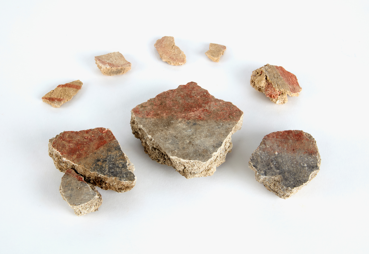 En samling av fragment av målad puts och bruk med kalkputs och bemålning. 17 fyndaskar med fragment i olika storlekar.

Fyndask 1: Totalt 13 fragment med röd och vit färg, en ser ut att ha träavtryck (varit fäst mot ett trästycke).

Fyndask 2: Totalt 7 fragment alla utom en har röd och vit färg, endast en med gråaktig obehandlad puts. 

Fyndask 3: Totalt 1 större fragment med röd och vit färg på enda sidan.

Fyndask 4: Totalt 4 fragment alla utom en med röd och vit färg, endast en med vit puts. 

Fyndask 5: Totalt 3 fragment med röd och vit färg, varav en är sotig. 

Fyndask 6: Totalt 3 fragment med röd och vit färg, en mycket tydlig medan de andra två mer diffusa. 

Fyndask 7:  Totalt 27 fragment, 24 av dessa är bemålade med röd och vit färg, 3  fragment med gråaktig obehandlad puts. 

Fyndask 8: Totalt 5 fragment, varav 4 större och en mycket liten. Alla större fragment med olika karaktär. En med vit kalkbruk och utan putsad yta, en annan med svart och röd putsad yta. Det tredje fragmentet har lite rödfärgad puts bevarad och på andra sidan ser det ut att ha träavtryck (varit fäst mot ett trästycke). Det fjärde fragmentet har en mer brungrå nyans. I fyndasken låg en lapp med text N. om V. portalen. 

Fyndask 9: Totalt 13 fragment, varav ett större fragment med svart och rödmålad puts. Ett annat fragment med svart och vitmålad puts, det tredje fragmentet har endast svartmålad puts. Sedan finns tre rödmålande putsfragment, samt tre fragment med röda linjer. Fyra fragment är ytterst små och intetsägande.

Fyndask 10: Totalt 9 fragment samt smådelar varav två har rött färgfragment. Det största fragmentet samt fyra andra är svart- och rödmålat. Tre putsfragment har röda linjer.
 
Fyndask 11: Totalt 1 fragment med röda linjer samt en mindre del med blågråa linjer. 

Fyndask 12: Totalt 1 fragment med blågrå rundad linje samt samt en mindre punkt eller koncentration nedanför.  

Fyndask 13: Totalt 5 fragment varav två med rödmålad puts. De andra tre har linjer. 

Fyndask 14: Totalt 1 fragment med vit och rödmålad puts, med flertal linjer som eventuellt kan vara del av en bokstav.
 
Fyndask 15: Totalt 1 fragment med vit och svartmålad puts, med flertal linjer som eventuellt kan vara del av en större figur. Ena delen syns en större koncentration som skulle kunna vara en fågel. 

Fyndask 16: Totalt 1 fragment med vit och rödmålad puts, med flertal rundade linjer som eventuellt kan vara del av växtlig dekor.

Fyndask 17: Totalt 1 fragment med rödmålad puts, med en vit linje.