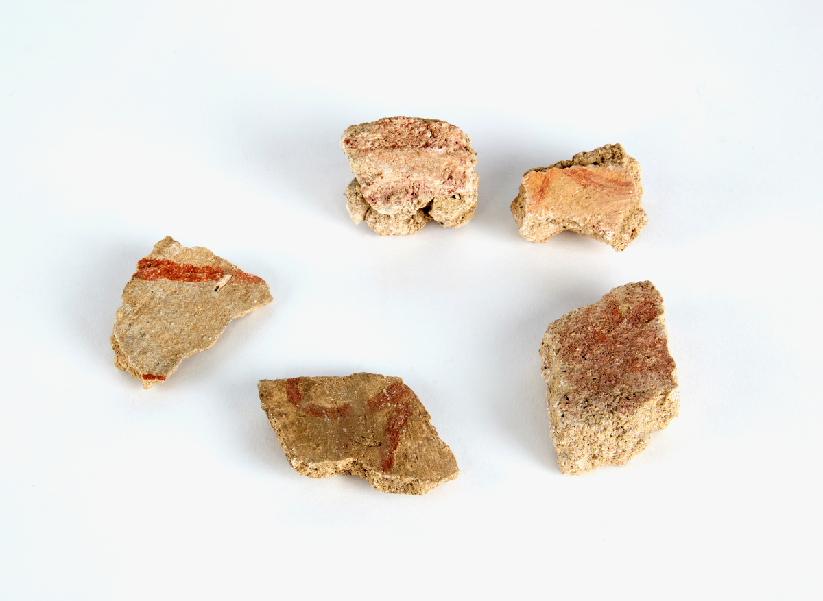 En samling av fragment av målad puts och bruk med kalkputs och bemålning. 17 fyndaskar med fragment i olika storlekar.

Fyndask 1: Totalt 13 fragment med röd och vit färg, en ser ut att ha träavtryck (varit fäst mot ett trästycke).

Fyndask 2: Totalt 7 fragment alla utom en har röd och vit färg, endast en med gråaktig obehandlad puts. 

Fyndask 3: Totalt 1 större fragment med röd och vit färg på enda sidan.

Fyndask 4: Totalt 4 fragment alla utom en med röd och vit färg, endast en med vit puts. 

Fyndask 5: Totalt 3 fragment med röd och vit färg, varav en är sotig. 

Fyndask 6: Totalt 3 fragment med röd och vit färg, en mycket tydlig medan de andra två mer diffusa. 

Fyndask 7:  Totalt 27 fragment, 24 av dessa är bemålade med röd och vit färg, 3  fragment med gråaktig obehandlad puts. 

Fyndask 8: Totalt 5 fragment, varav 4 större och en mycket liten. Alla större fragment med olika karaktär. En med vit kalkbruk och utan putsad yta, en annan med svart och röd putsad yta. Det tredje fragmentet har lite rödfärgad puts bevarad och på andra sidan ser det ut att ha träavtryck (varit fäst mot ett trästycke). Det fjärde fragmentet har en mer brungrå nyans. I fyndasken låg en lapp med text N. om V. portalen. 

Fyndask 9: Totalt 13 fragment, varav ett större fragment med svart och rödmålad puts. Ett annat fragment med svart och vitmålad puts, det tredje fragmentet har endast svartmålad puts. Sedan finns tre rödmålande putsfragment, samt tre fragment med röda linjer. Fyra fragment är ytterst små och intetsägande.

Fyndask 10: Totalt 9 fragment samt smådelar varav två har rött färgfragment. Det största fragmentet samt fyra andra är svart- och rödmålat. Tre putsfragment har röda linjer.
 
Fyndask 11: Totalt 1 fragment med röda linjer samt en mindre del med blågråa linjer. 

Fyndask 12: Totalt 1 fragment med blågrå rundad linje samt samt en mindre punkt eller koncentration nedanför.  

Fyndask 13: Totalt 5 fragment varav två med rödmålad puts. De andra tre har linjer. 

Fyndask 14: Totalt 1 fragment med vit och rödmålad puts, med flertal linjer som eventuellt kan vara del av en bokstav.
 
Fyndask 15: Totalt 1 fragment med vit och svartmålad puts, med flertal linjer som eventuellt kan vara del av en större figur. Ena delen syns en större koncentration som skulle kunna vara en fågel. 

Fyndask 16: Totalt 1 fragment med vit och rödmålad puts, med flertal rundade linjer som eventuellt kan vara del av växtlig dekor.

Fyndask 17: Totalt 1 fragment med rödmålad puts, med en vit linje.