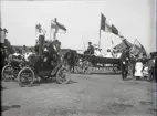 Förberedelser inför den stora Barnens Dag-paraden i Varberg,
Förutom en stor eka, apterad som vagn, syns en Oldsmobile från cirka 1903. 
Modellen kallades ofta Curved Dash på grund av karossens utseende, och i Sverige kallades den spakolds eftersom 
den styrs med spak i stället för ratt.
Vid den här tiden ägdes en dylik Oldsmobile av doktor Johan Severin Almer (1861-1927) som grundade Kusthotellet
i Varberg. Möjligen är det hans bil på bilden.