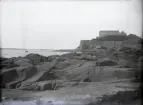 Vy över Varbergs fästning från ett klippigt strandparti.