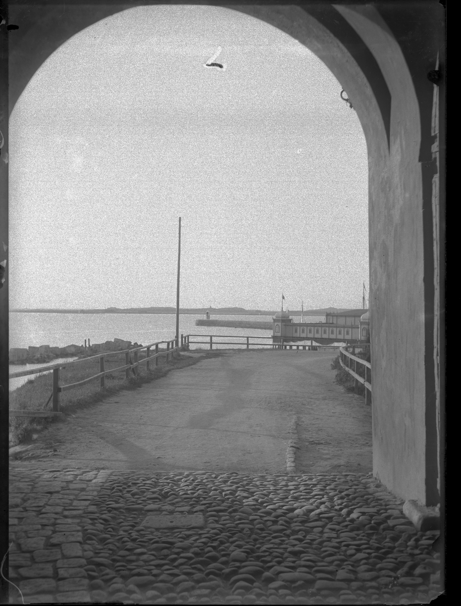 Vy från en av fästningsportarna mot hamnen och kallbadhuset, som skymtar till höger.