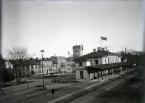 Järnvägsstationen i Växjö, trol. en tidig morgon. Flaggan (med unionsmärke) är hissad. Bakom stationen syns husen vid Norra Järnvägsgatan  (kvart. Linné) och domkyrkans torn.