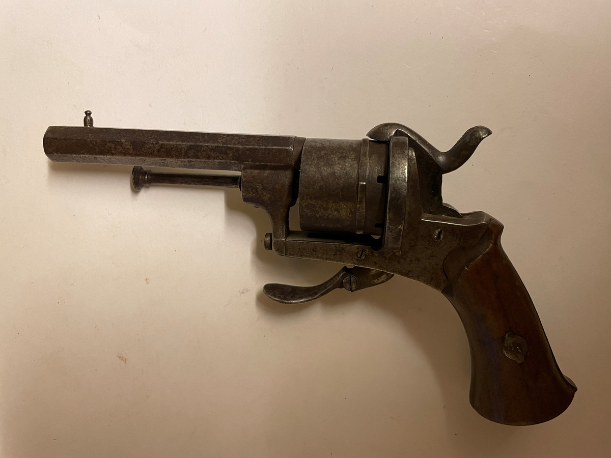 Revolver från Belgien i kalibern 7 mm, för stiftantändningspatron. Liegestämplar på trumman. Kolv av valnötsträ. Modellen är utan varbygel.

Tillverkningsnummer: 9594