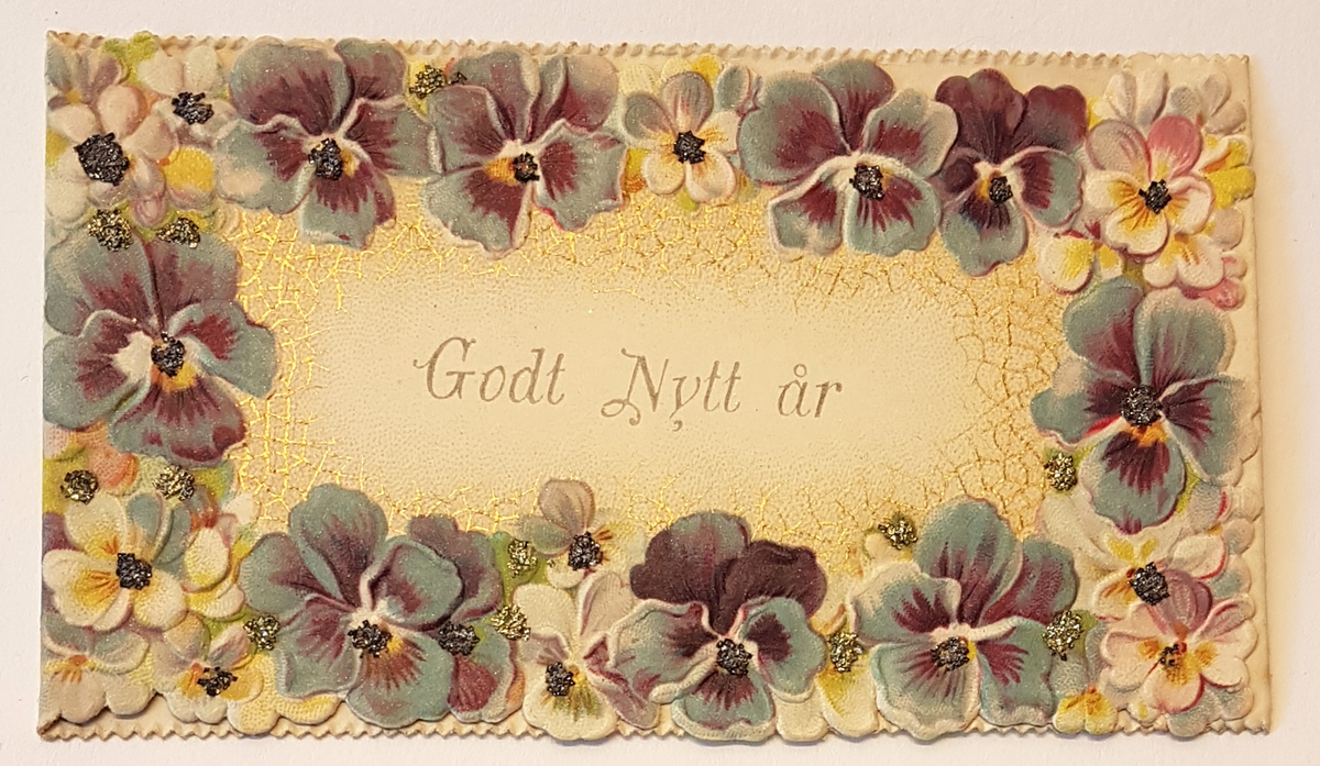 Nyårskort med motiv av violer i lila och blå toner och detaljer i guld. Godt Nytt år i guldskrift i kortets mitt.  På insidan en tryckt nyårshälsning, signerad L.S