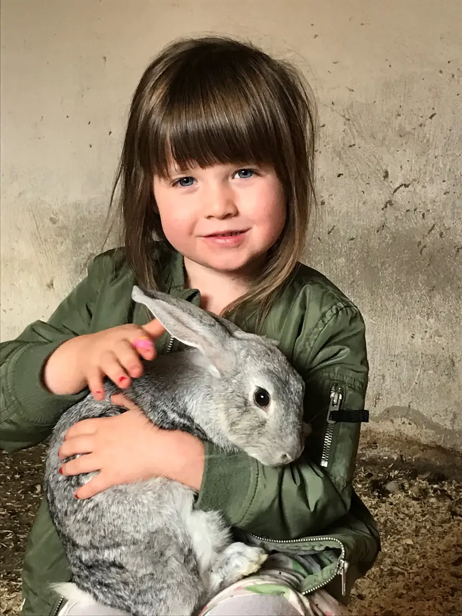 Flicka sitter med en kanin i famnen