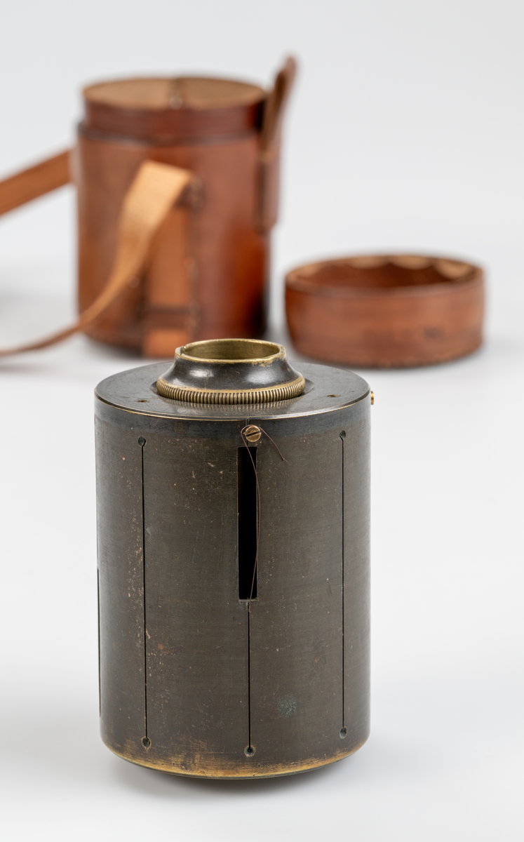 Cylindriskt mätinstrument av metall. Med tillhörande läderetui. Sammanbunden på rem med M 21553. 

Givarens fader länsjägmästare Olof Hjalmar Humble, var på slutet av 1800-talet dikningsassistent på Gävle-Dala distriktet, och använde då dessa instrument.
Funktion: Stakning av skogsdiken
